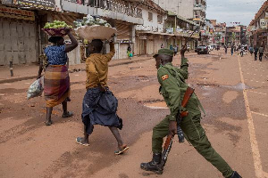 A police officer beats a female orange vendor on a street in Kampala, | BADRU KATUMBA | AFP