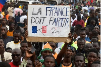 Protesters hold an anti-France placard during a demonstration on independence day in Niamey