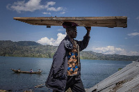 A man carries a door from his home on his head to a makeshift house after the flooding disaster