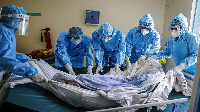 Medical team rolls a coronavirus patient from a bed onto a stretcher