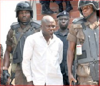 Johnson Kombian in police grip