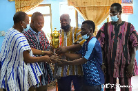 A member of the playing presenting the cup to the chief and his elders