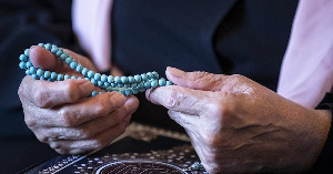 Retired Egyptian civil servant holds blue prayer beads during an interview