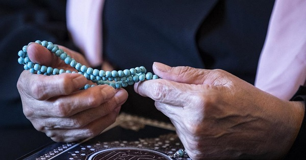 Retired Egyptian civil servant holds blue prayer beads during an interview