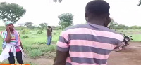 People spread out under a moringa tree in the forest to get mobile network connections