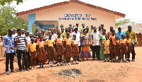 Bank officials, teachers, pupils of Akotoe Tsrebuana D/A Primary standing close to the bungalow