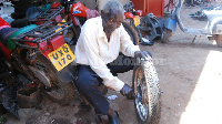 Lwanga repairs a motorcycle tyre. He has been repairing motorcycles since 1957