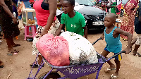 An image of a child pushing a load at the Agomanya market