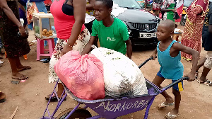 An image of a child pushing a load at the Agomanya market