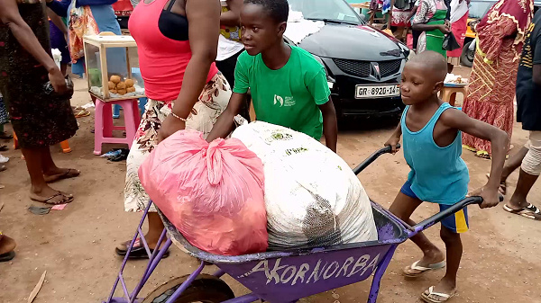 An image of a child pushing a load at the Agomanya market