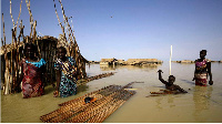 South Sudanese refugees try to repair their hut in flooded waters from the White Nile