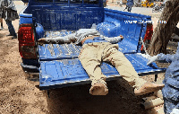 The robber lying in the bucket of the police pickup