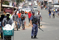 A policeman looks on as locals go on their daily business on the first day of a nationwide lockdown