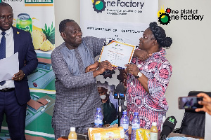 Madam Gifty Ohene Konadu presenting a certificate to a represnetative of one of the 1D1F companies