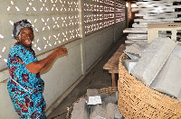 Beatrice Awudey pointing at the empty trays lying idle at the factory