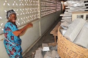 Beatrice Awudey pointing at the empty trays lying idle at the factory