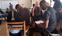 A photo of some students sitting on chair handles