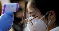 A worker checks the temperature of a woman at a mask factory in Shanghai, REUTERS/Aly Song