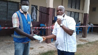 Stephen Ntim presenting nose masks to a staff of the EC