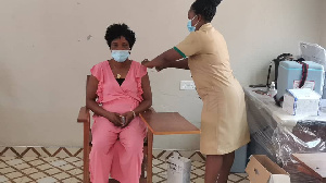 A health personnel administering COVID-19 vaccine to a woman