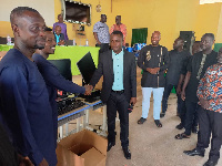 The headmaster of the school (in suit) receiving the computers