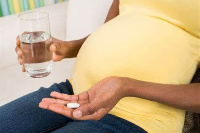 Pregnant mother readies to take a pill | File photo