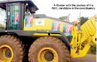 Grader with posters of an NDC candidate in the Area