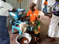 A women from the community operating a grinding mill from a project centre