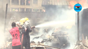 A resident cooling off some firefighters with a bucket of water