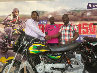 Tamimu Issah receiving the motorcycle from a rep of Somoco