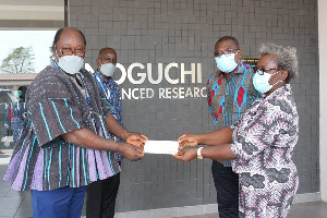 Mrs. Mary Degollo being supported by Mr. Emmanuel Sengretsi to hand over the cheque to Prof. Abraham