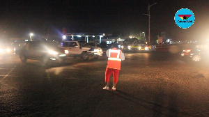 Mrs. Margaret Ansah using the flashlight from her phone to direct traffic at Madina Ritz junction