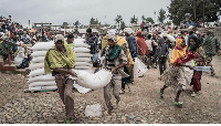 Men carry a sack of wheat during food aid distribution by WFP for IDPs in Debark, Ethiopia