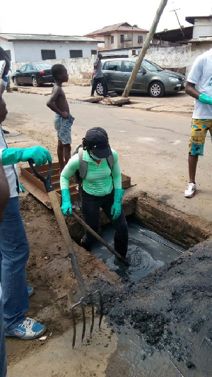 Dr. Zanetor Rawlings desilting Nkrumah Circle choked gutters with a shovel