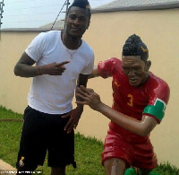 Asamoah Gyan [left] poses for a picture with the statue