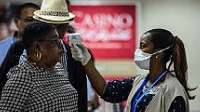 A Haitian health department employee scans the body temperature of an incoming travellers