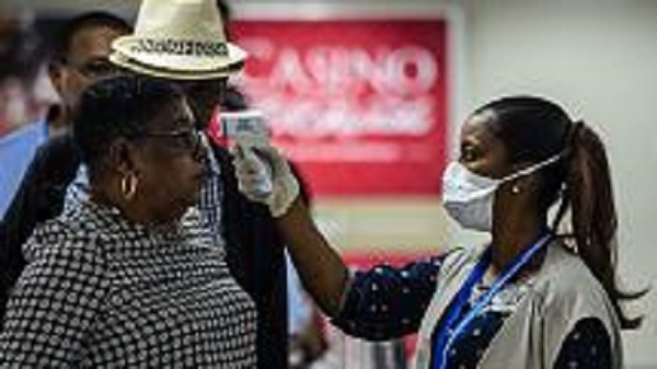 A Haitian health department employee scans the body temperature of an incoming travellers