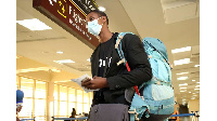 A passengers waits to undergo clearance and body temperature checks after arriving at the JKIA