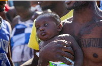 Asylum seeker carries a child near the seashore, at the Libyan-Tunisian border in Ras Ajdir, Libya