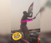 The man is spotted with two NDC flags standing on a taxi