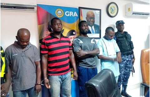 The four suspects in handcuffs and being guarded at the GRA office during the press briefing