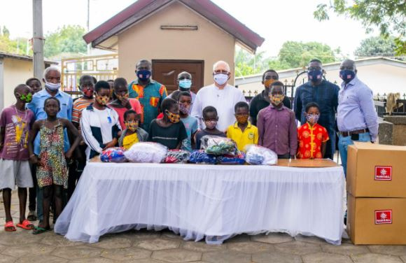 Fr Andrew Campbell  receiving items from  MASK4ALL Ghana