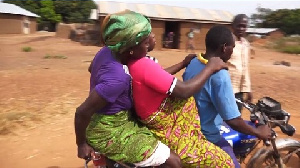 A pregnant woman sandwiched by two other persons on a motorbike