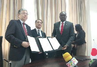 From R-L: Charles A. Owiredu, Tsutomu Himeno and Hirofumi Hoshi exchanging documents