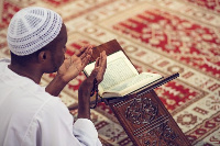 A Muslim praying and reading the Quran