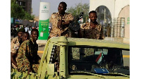 Sudanese soldiers are seen on an army vehicle as they drive through the defense ministry compound