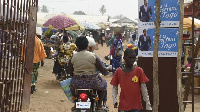 A motorbike taxi drive past campaign banners.