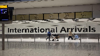 Arriving passengers walk past a sign in the arrivals area at Heathrow Airport in London