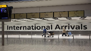 Arriving passengers walk past a sign in the arrivals area at Heathrow Airport in London