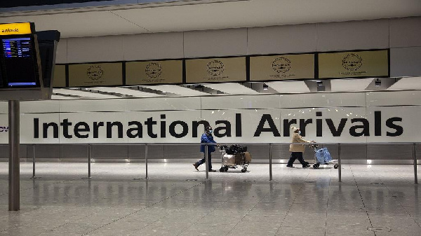 Arriving passengers walk past a sign in the arrivals area at Heathrow Airport in London